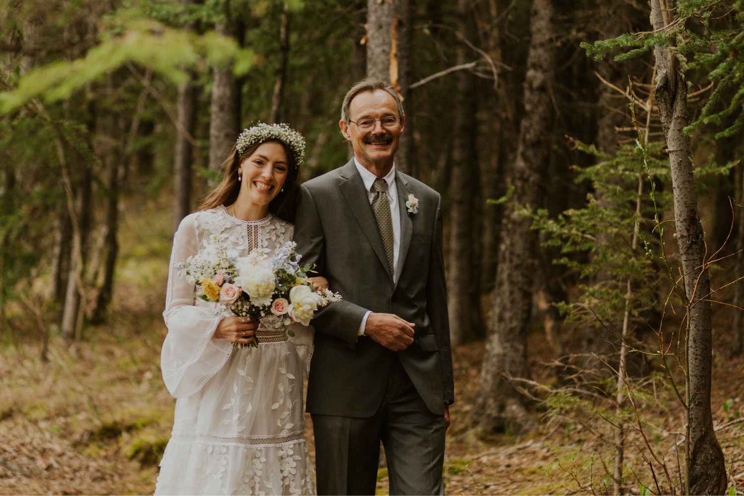 A Kananaskis Lake Elopement in the beautiful Canadian Rockies photo of bride walking down the forest with her dad