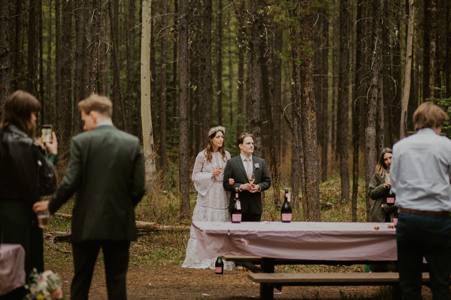 A Kananaskis Lake Elopement in the beautiful Canadian Rockies photo of outdoor reception in the forest with toasts and laughs