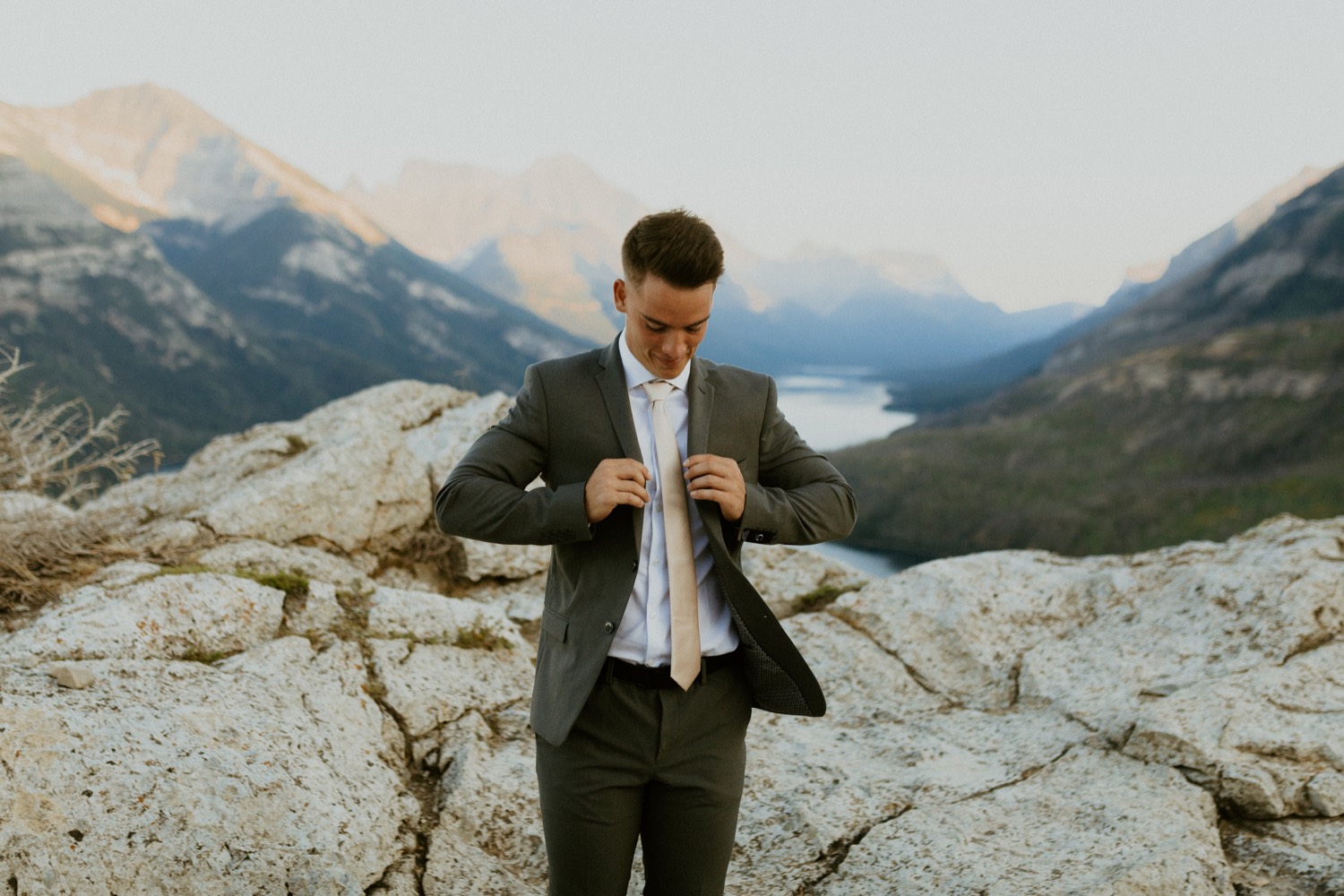 Waterton Wedding Adventurous Mountain Elopement style in the beautiful Canadian Rocky Mountains groom fixing his tie on the mountain top