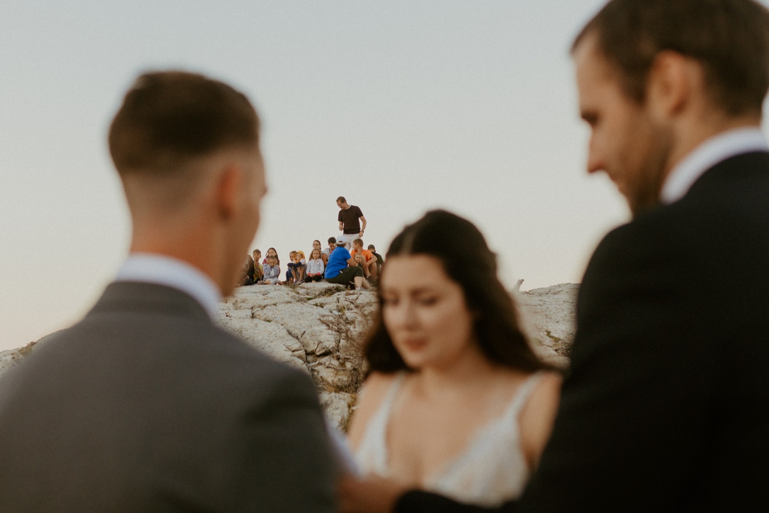 Waterton Wedding Adventurous Mountain Elopement style in the beautiful Canadian Rocky Mountains ceremony at the mountain top with close friends and officiant with crowd watching from behind