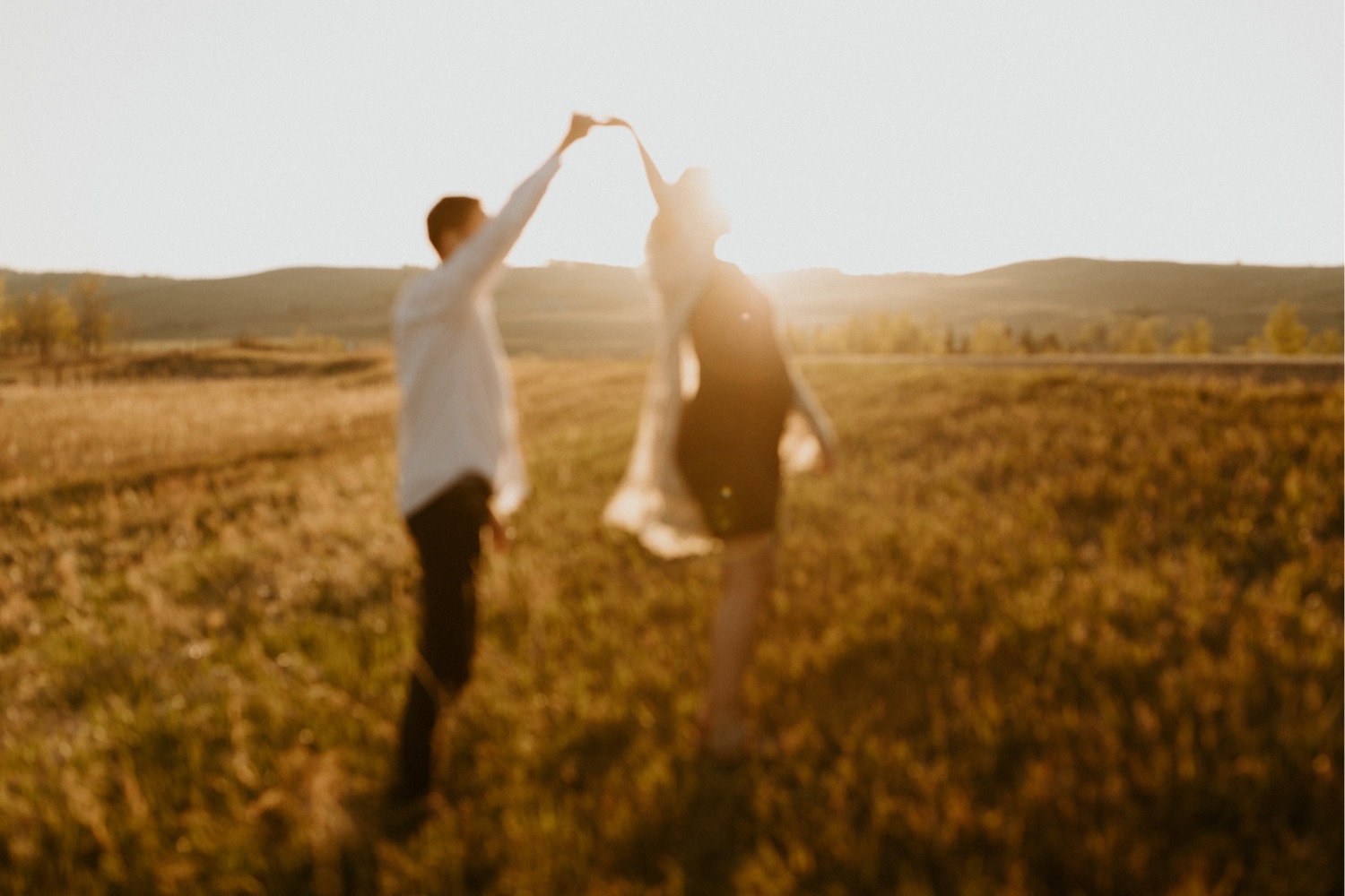 Maternity Family Photos in Calgary with mother and father dressed up for their pregnancy photoshoot with white flowy dress and baby boy in mothers belly near the mountains in Calgary Alberta during a beautiful sunset, maternity lifestyle photos in Calgary, casual lifestyle maternity photoshoot, baby photos