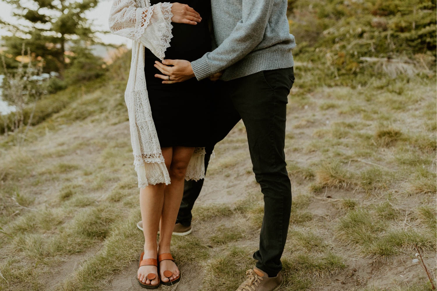 Maternity Family Photos in Calgary with mother and father dressed up for their pregnancy photoshoot with white flowy dress and baby boy in mothers belly near the mountains in Calgary Alberta during a beautiful sunset, maternity lifestyle photos in Calgary, casual lifestyle maternity photoshoot, baby photos